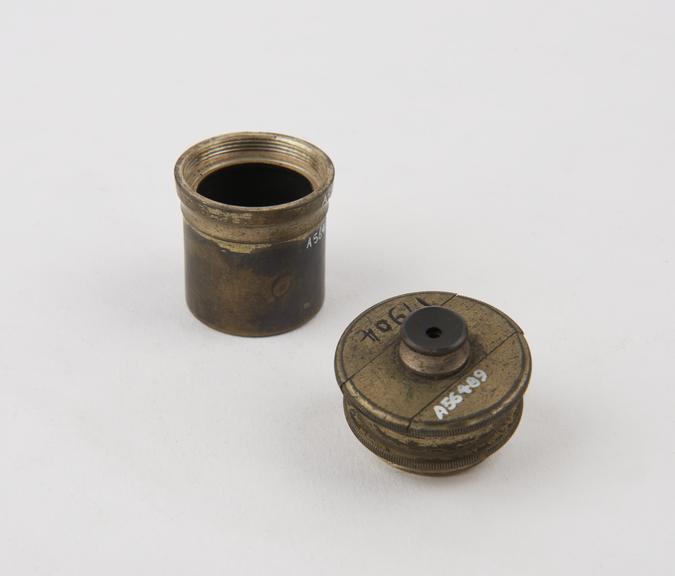 Small cannister, containing lens set in tube