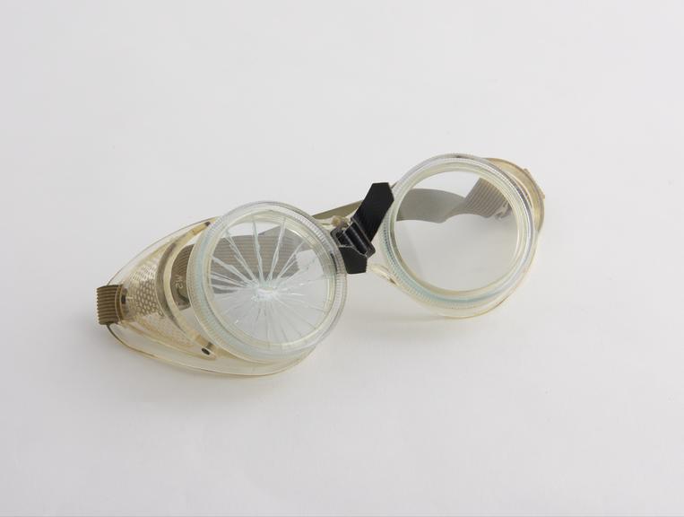 Pair of safety glass goggles, one side normal, one side cracked