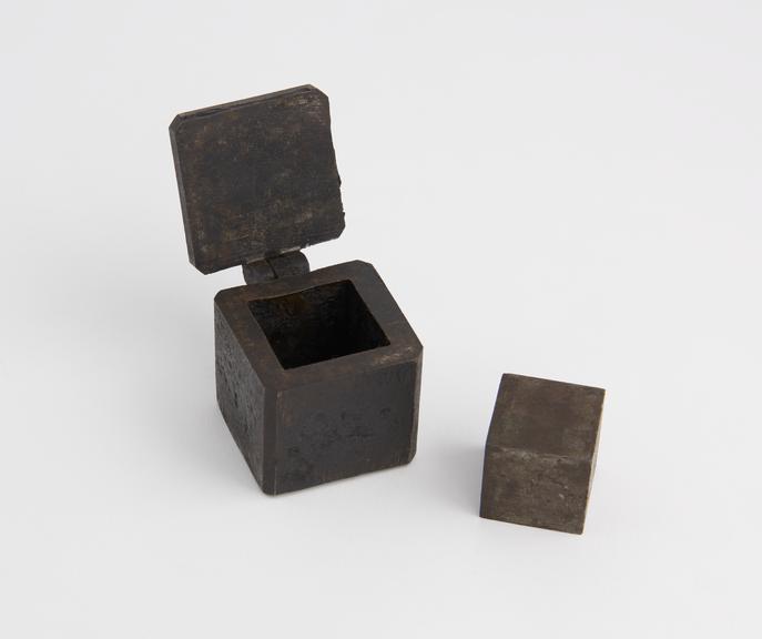 Iron box, hinged lid, enclosing iron cube