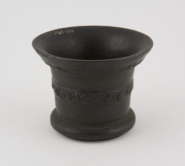 Bronze mortar with crude leafy decoration round the outside rim