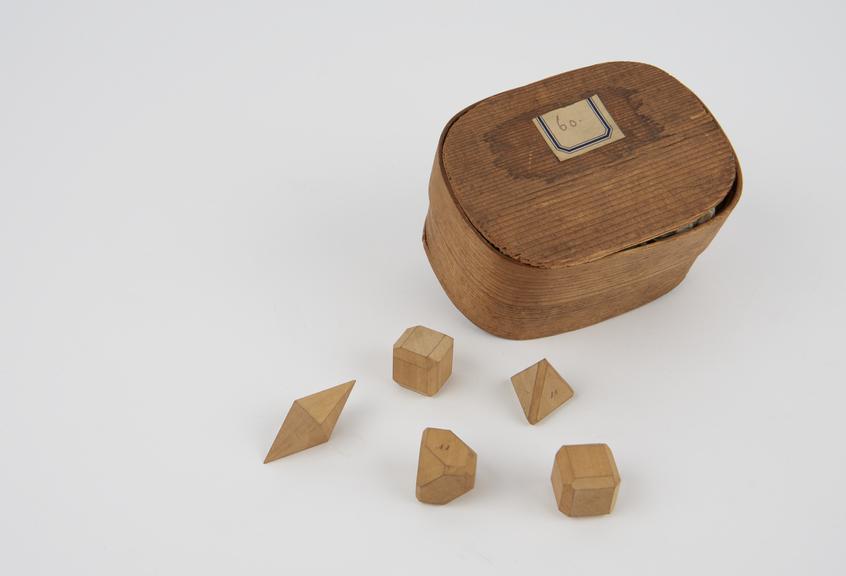 Oval box containing 5 geometrical solids numbered 26, 27, 28