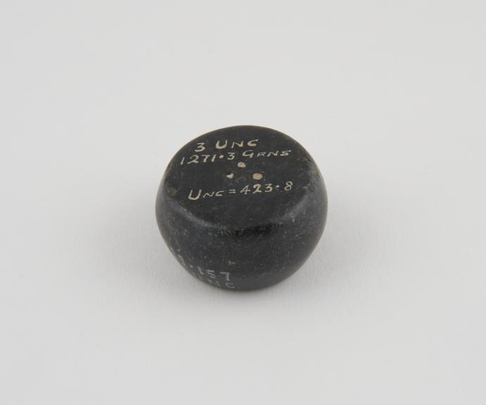 One of 15 Roman weights, cheese-shaped, polished black basalt