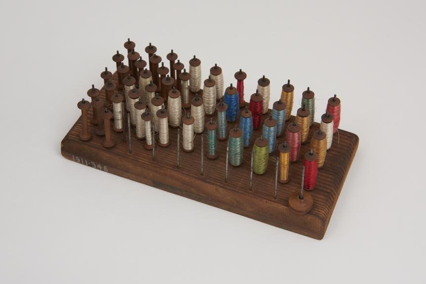 Full and empty miniature bobbins on wooden stand