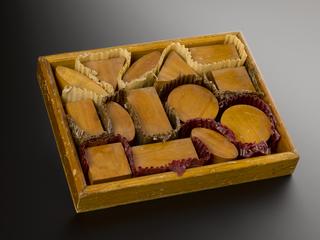 Biscuit Packers' test comprising tray holding four wooden "biscuit" shapes and three thin strips of corrugated cardboard to "wrap" them with