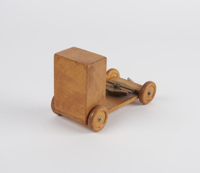 Model vehicle made from wood.  It has 4-wooden wheels.