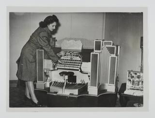 A photograph of a woman demonstrating a Wurlitzer organ