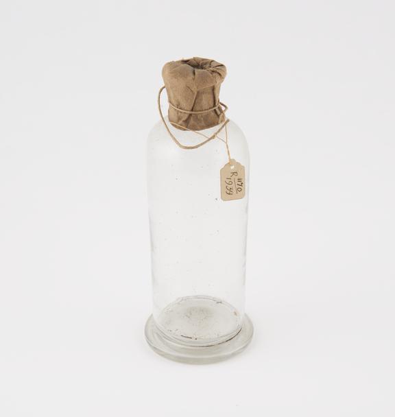 Bottle with neck wrapped in paper apparently to keep the inside