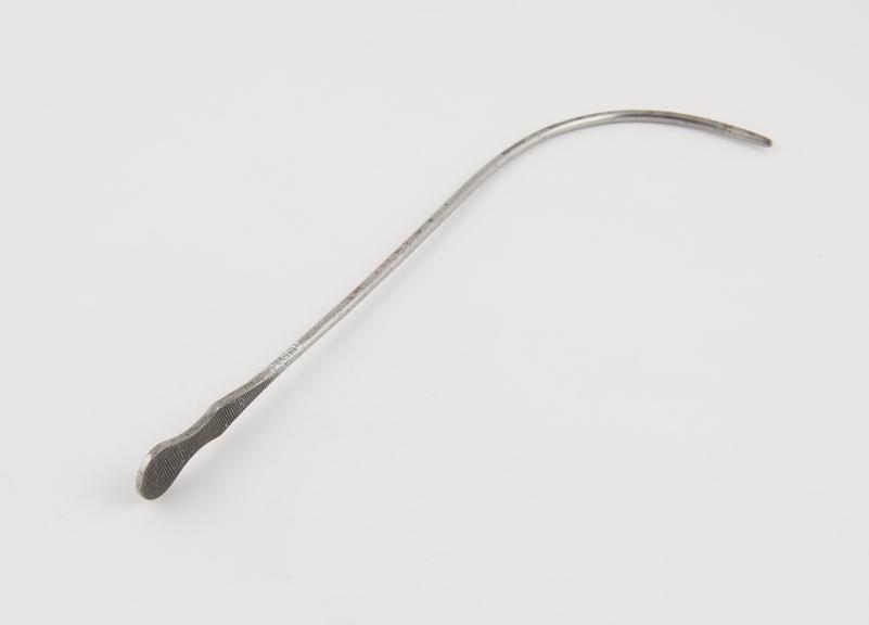 Small curved lithotomy staff with median groove and flat handle