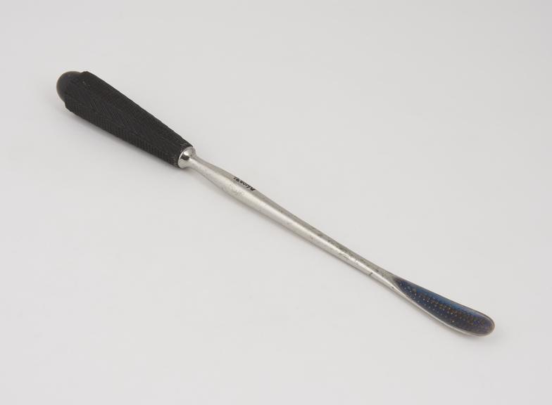 Long lithotomy scoop with shallow elongated blade and chequered