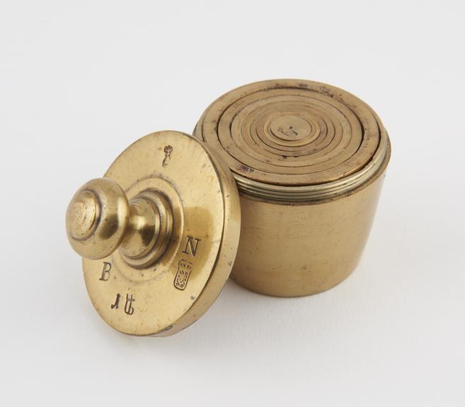 Set of nested brass weights in screwtop case which forms the