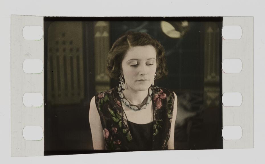 Single frame of silent 35mm stencil colour film showing a woman