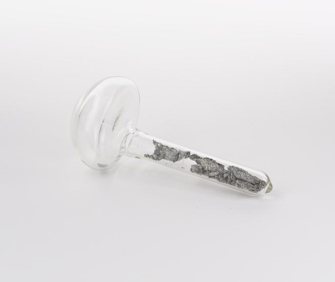 Mushroom shaped glass vial containing holmium, atomic number 67.