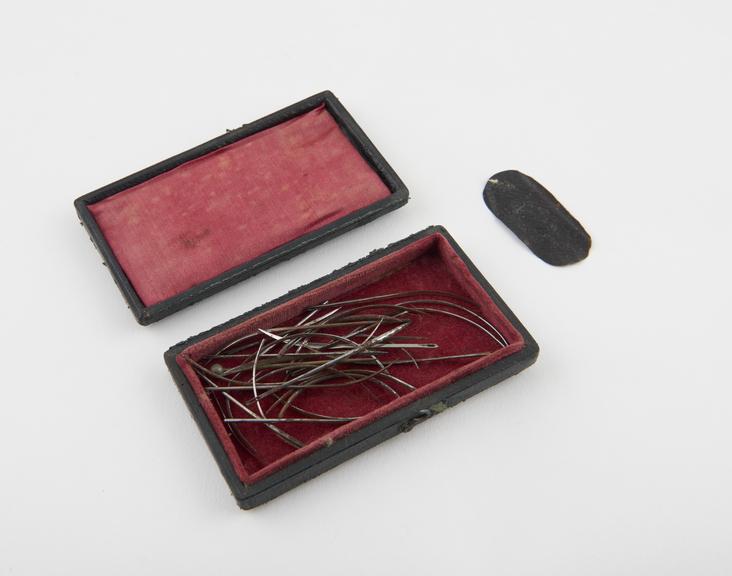 An assortment of suture needles, steel, in leather case