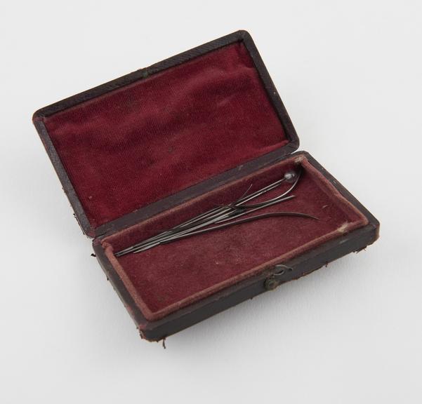 8 suture needles and a hare lip pin, steel, in leather case