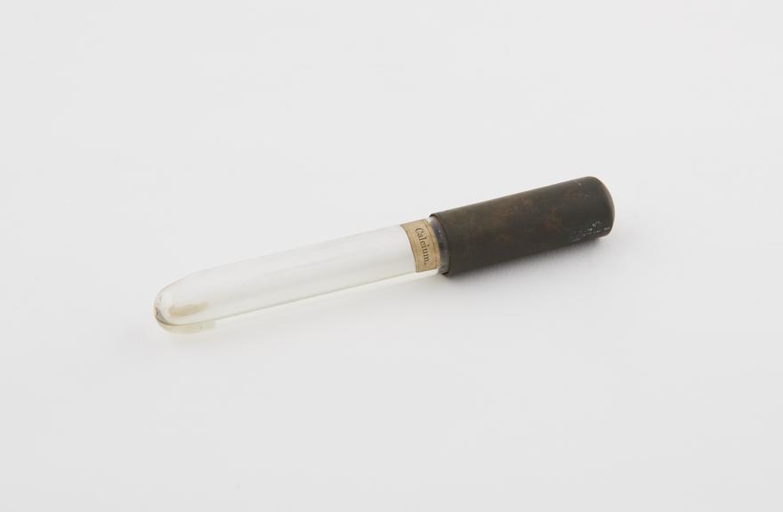 Glass vial with metal cap containing calcium regulus in rock