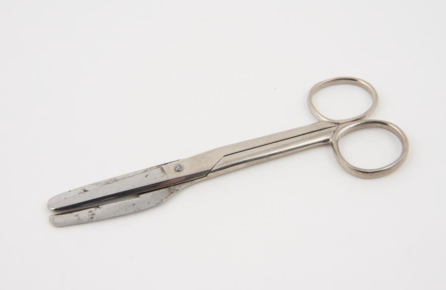 A pair of circumcision scissors with one cleft blade and one