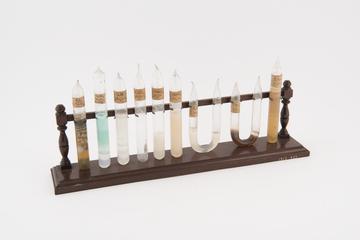 Nine specimens illustrating reactions in gels on a wooden stand