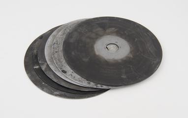 Metal recording discs from a clockwork motor and shutter assembly from Dobson Spectrophotometer