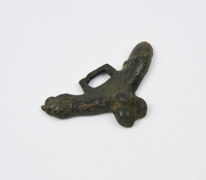 Bronze pendant in form of arm over male genitalia