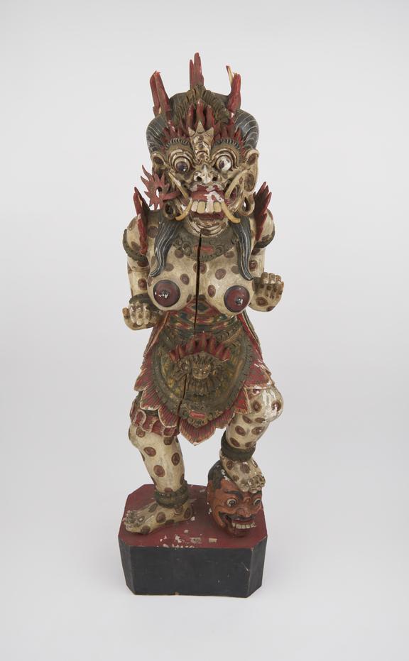 Painted wooden figure of female demon with left foot planted on