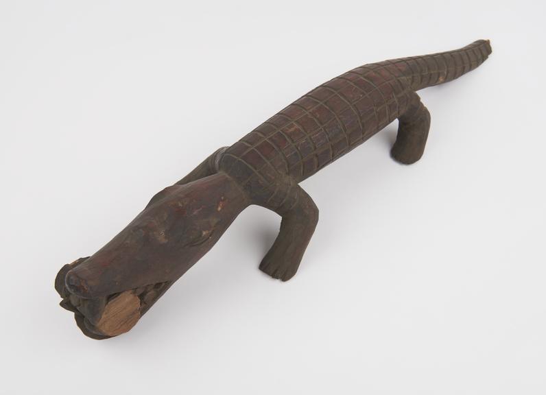 Carved wooden lizard or alligator with something in jaws