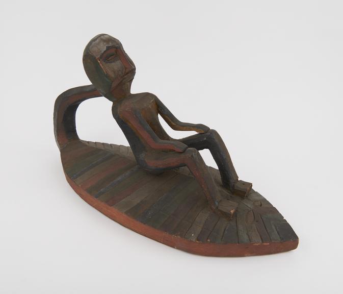 Carved, wooden figure seated in boat, probably amuletic