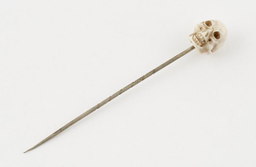 Metal tie or hat pin with a shell knob in the form of a skull