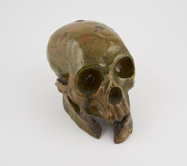 Green, glazed, earthenware human skull, lower jaw damaged