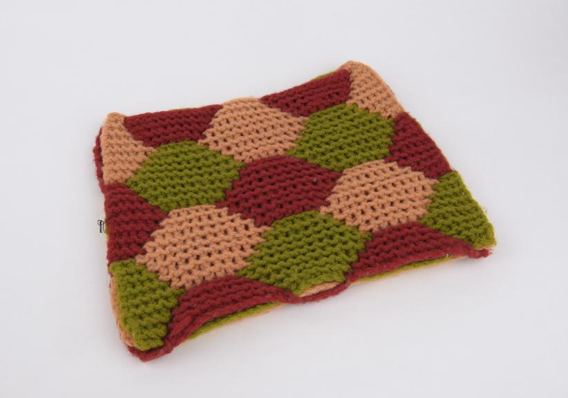 Knitted interlacing surfaces in green, red and pink wool