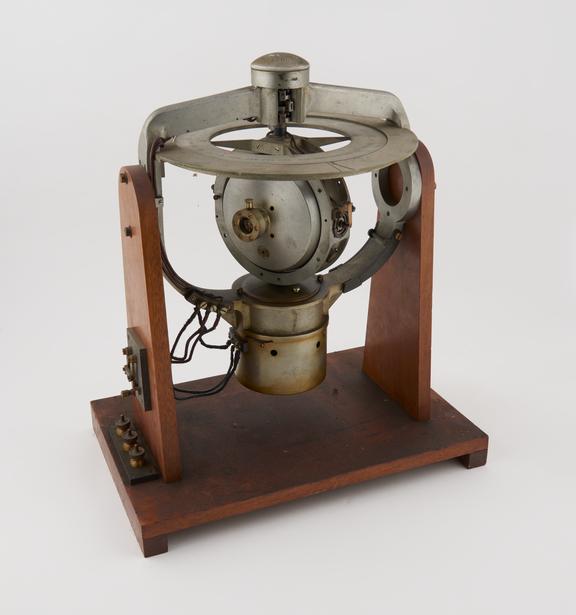 Brown gyro compass, mounted in gimbals, on wooden stand