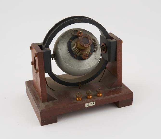 Brown gyro compass, mounted in vertical gimbal, on wooden stand