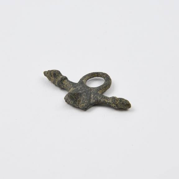 Amuletic bronze(?) pendant in form of phallic cross with one