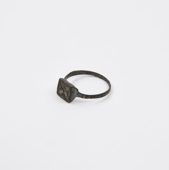 Bronze finger ring with square bezel bearing engraved four-lobed flower