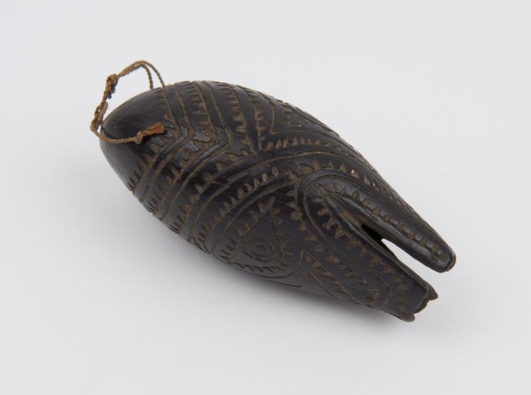 Amulet consisting of block polished immature coconut carved to