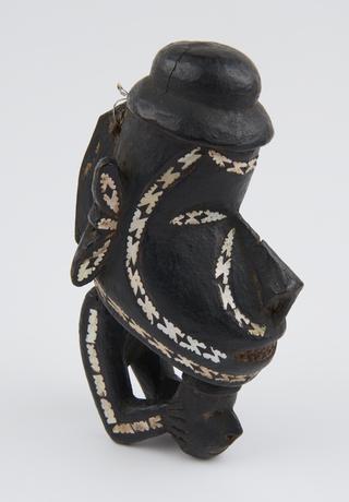 Carved canoe prow figure painted black and inlaid with mother-of-pearl