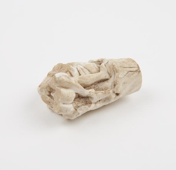 Carved marble fragment showing legs of a copulating couple with acanthus leaves