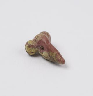 Small red stone bead carved in form of male genitalia