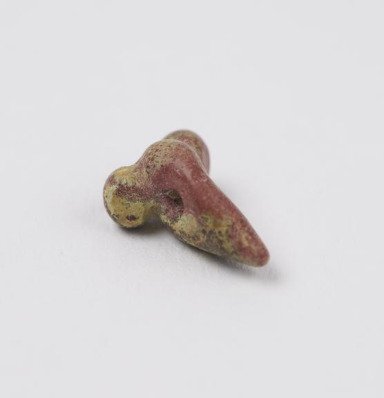 Small red stone bead carved in form of male genitalia