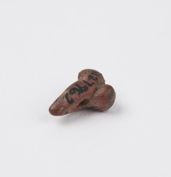 Small red stone bead carved in form of male genitalia