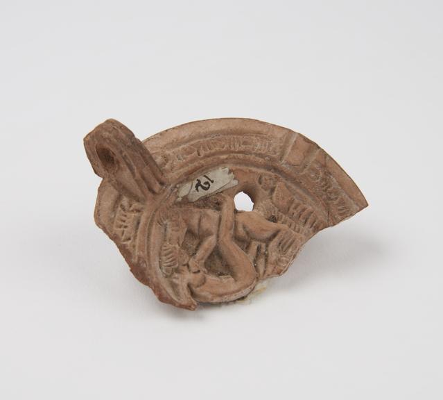 Broken fragment of terracotta lamp with moulded design of human