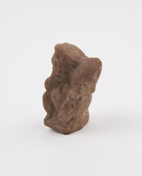 Amulet in form of terracotta figure of ithyphallic seated child with hand to mouth