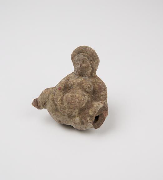 Small red stone bead carved in form of male genitalia