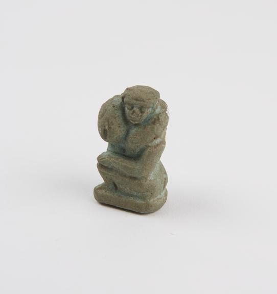 Small solid faience figure of squatting male with huge phallus around shoulders (statue; phallus)