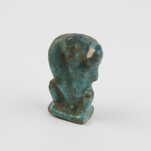 Small bluey green faience figure of a squatting male supporting huge phallus on his shoulders