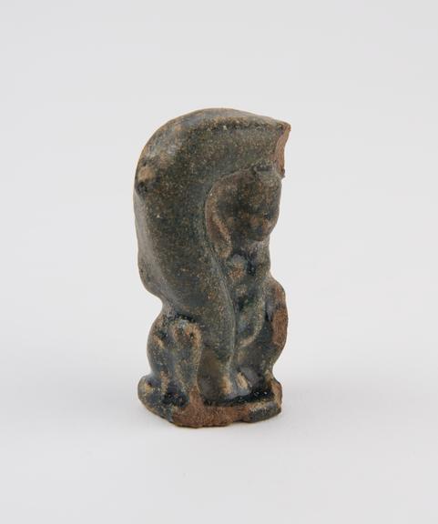 Small solid faience figure of squatting male supporting a huge