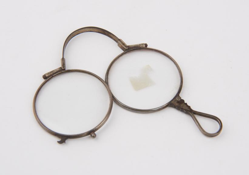 Silver folding spectacles with bow spring and round lenses.