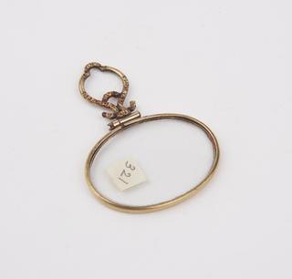Single oval eyeglasses in gold (?) frame with orna