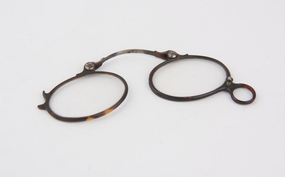 Pair of hand-held tortoiseshell rimmed folding spectacles with