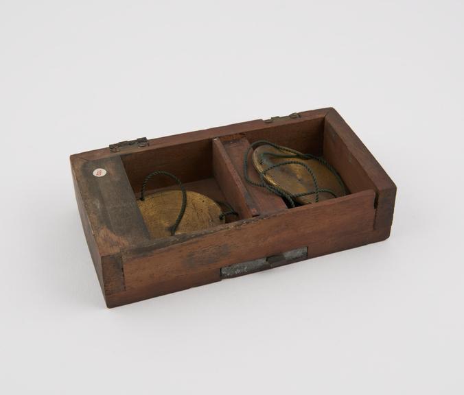 Pair of scale pans in box which appears to have been a door on