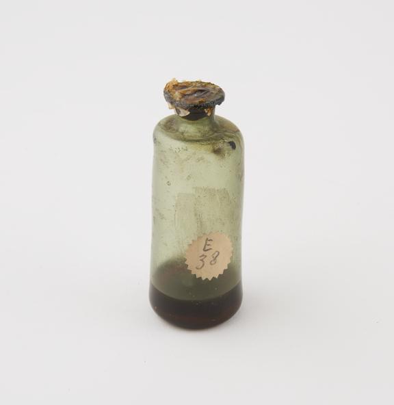 Green glass bottle with unidentified content, cylindrical